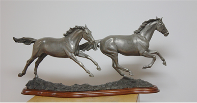 Bronze sculpture of horses galloping, titled Running Free